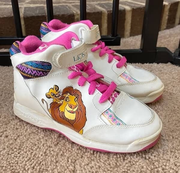 White high top Lion King sneakers with pink laces and tribal pattern.
