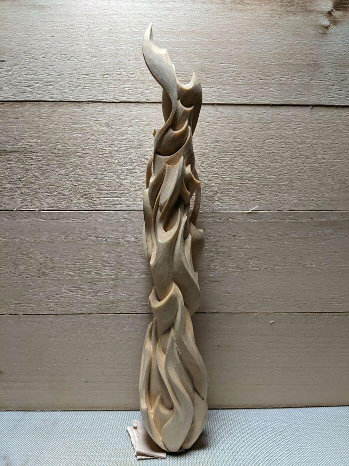 Tall vertical wood sculpture intricately hand carved to resemble swirling flames or smoke.