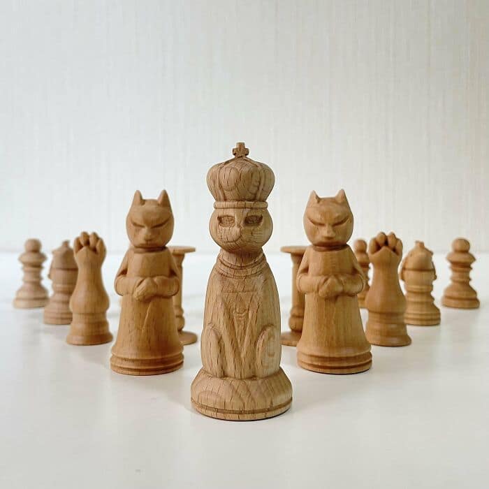 Hand-carved wooden chess set featuring detailed feline characters. Unique woodcraft showing cat queens and pawns.