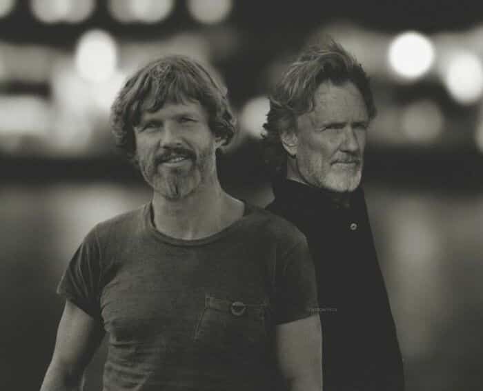 Kris Kristofferson standing back-to-back with his younger self.