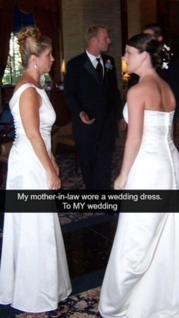 dramatic classic meme capture of a social nightmare: two women standing in a ballroom facing each other, both wearing nearly identical white wedding dresses. The caption reads, "My mother-in-law wore a wedding dress. To MY wedding."