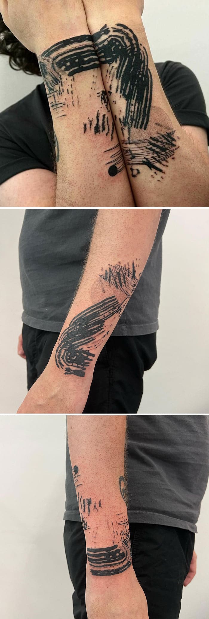 Abstract brushstroke forearm tattoos that form a continuous circular design when the arms are crossed.