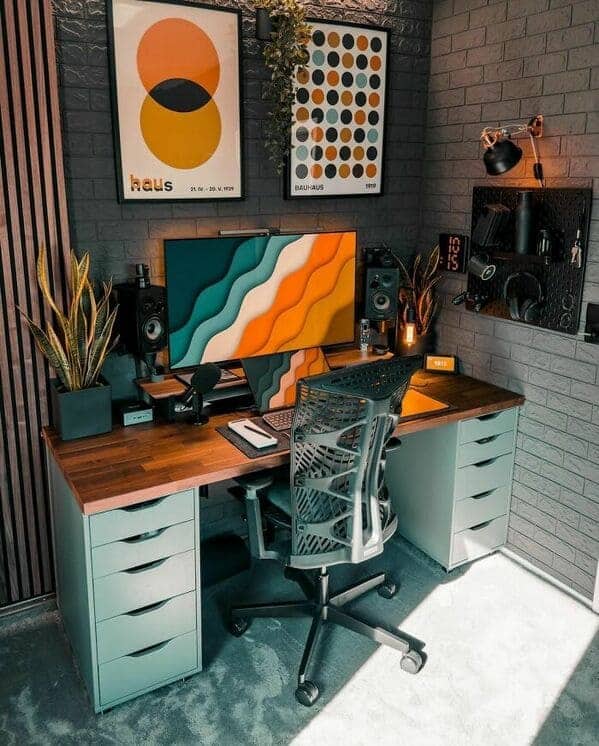 Stylish desk with grey brick wall, abstract colorful art, and mint drawers.