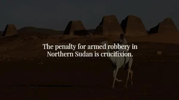 A person riding a camel past ancient pyramids in the desert illustrates a harsh creepy fact about the penalty for armed robbery in Northern Sudan being crucifixion.