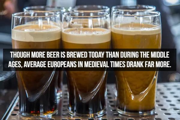 A row of dark, stout-style beers with thick, creamy heads sitting on a bar counter. The caption provides a comparative beer fact, noting that while we brew more beer today, the average medieval European actually consumed much more than we do now.