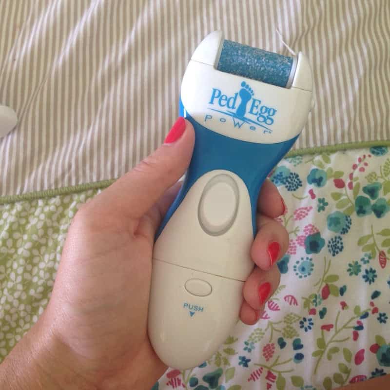 Ped Egg Power electric callus remover held in hand with red painted nails