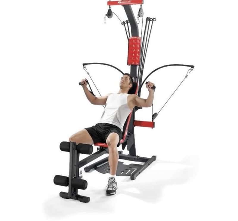 Man using Bowflex home gym cable resistance training machine in red and black