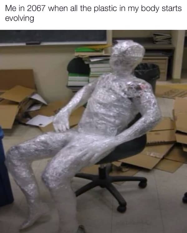 A person covered head to toe in plastic wrap sitting in an office chair.