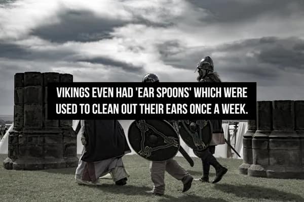 dramatic black and white photo of Viking warriors in helmets and tunics walking across a grassy field, highlighting a surprising historical fact that Vikings prioritized hygiene enough to use specialized "ear spoons" for weekly cleaning.