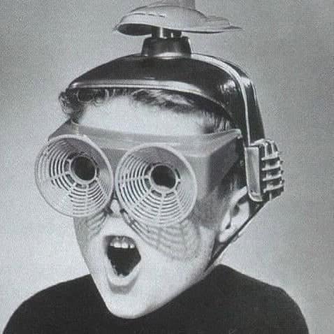 A young boy wearing a strange futuristic helmet and goggles stares in shock in this historical photo with no context.