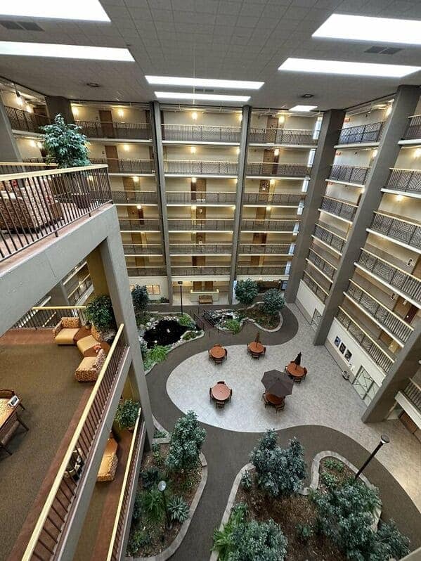 A creepy liminal space looking down into a massive, empty hotel atrium with many balconies.