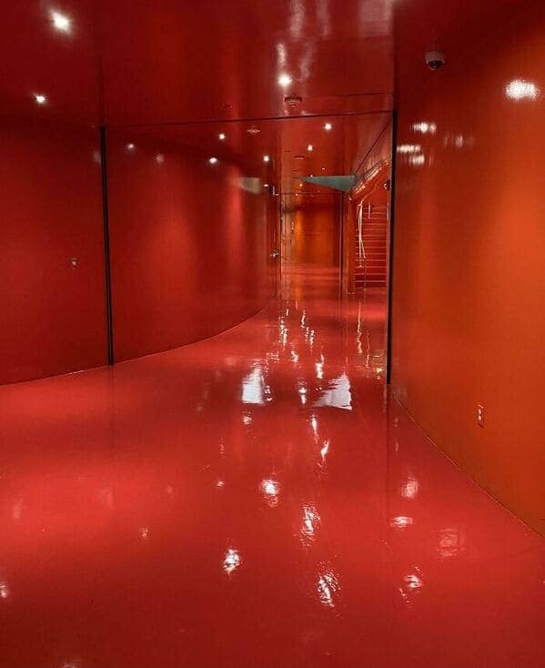 A creepy liminal space hallway painted entirely glossy red with reflective floors and walls.