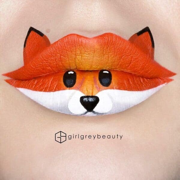 A stunning example of amazing lip art showing an adorable orange and white fox face cleverly painted across the upper and lower lips, capturing the signature, highly detailed Andrea Reed lip art style.