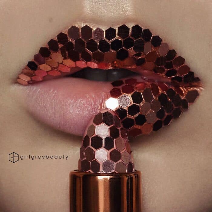 A glamorous and highly textured piece of amazing lip art using reflective copper hexagonal sequins applied perfectly across the lips and lipstick tube, typical of the innovative Andrea Reed lip art style.