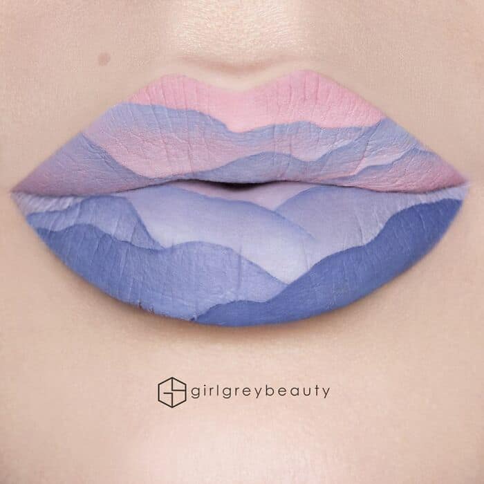 A soothing, pastel-toned masterpiece of amazing lip art depicting rolling mountain layers in soft, harmonious blues, purples, and pinks, highlighting the flawless gradient techniques of Andrea Reed lip art.