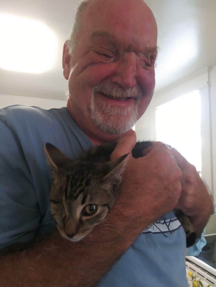 A heartwarming photo of a man and his cat both closing one eye in a matching wink.