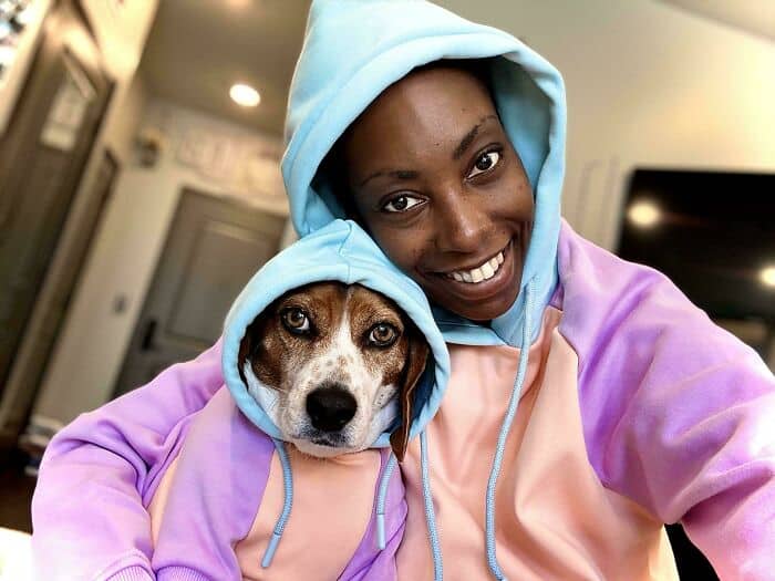 A woman and her beagle dog both wearing matching blue and purple pastel hooded sweatshirts.